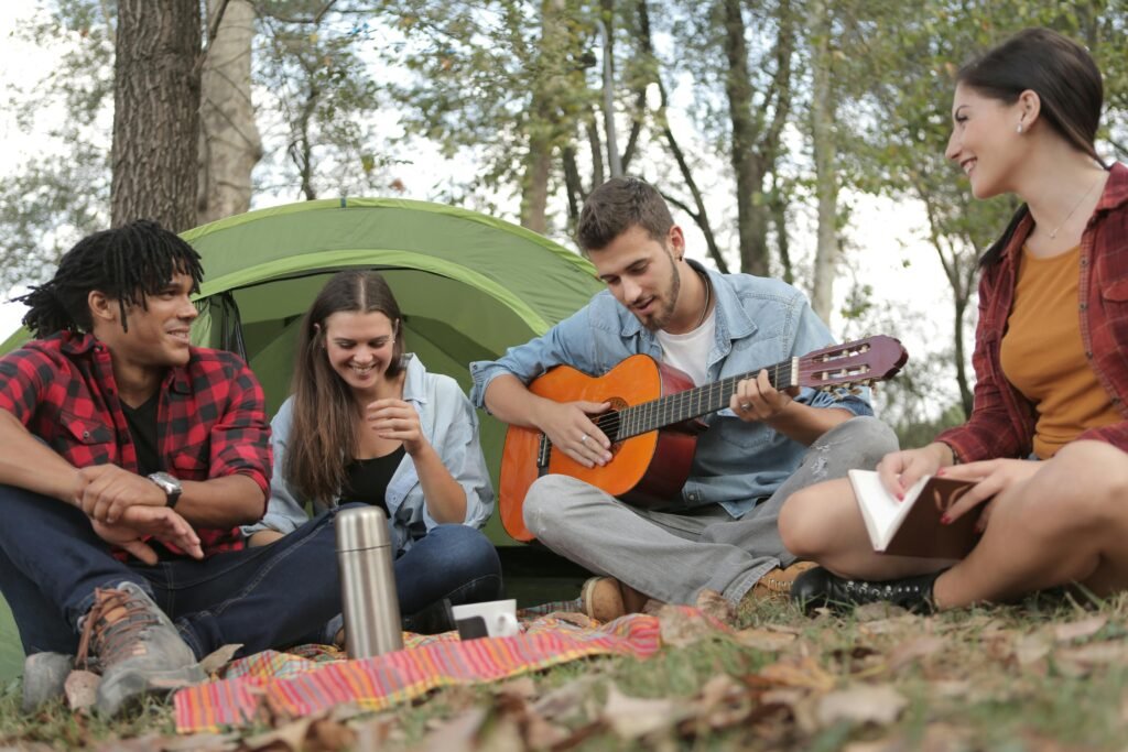 Online Vs Reality: 7 Differences for Those Searching for Casual Partners 4 Young friends camping and enjoying music together in a tranquil outdoor setting.