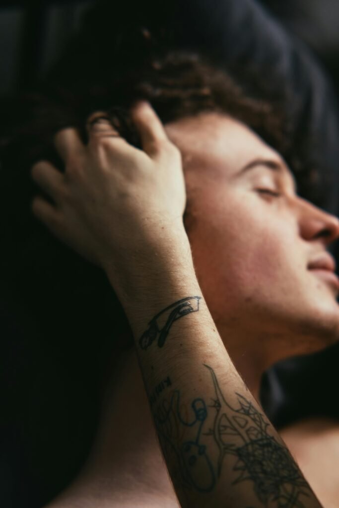 6 Reasons Why Casual Sex is Good for You 3 Close-up of a young man relaxing indoors, highlighting tattoos on his arm with a calm mood.